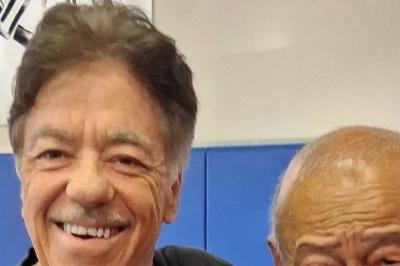 McElroy and Inosanto posed standing arms on shoulders smiling.