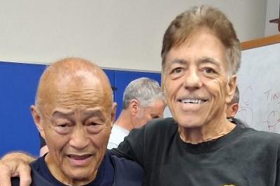 Sifu Dan Inosanto and Sifu McElroy standing side-by-side, smiling arms around shoulders