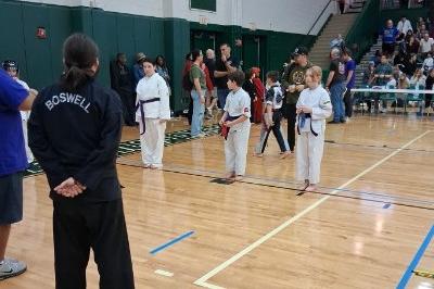 Three winners, including Abigail and Miles, standing before judges in middle of floor to receive ribbons.
