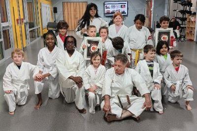 Young boy and girl students and Sifu McElroy posed with some showing framed awards