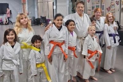Nine MMAA Boys and Girls with McElroy posed standing smiling wearing new belts - viewed from left