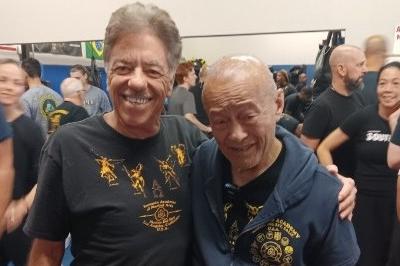 McElroy and Inosanto posed standing smiling wearing training t-shirts and pants
